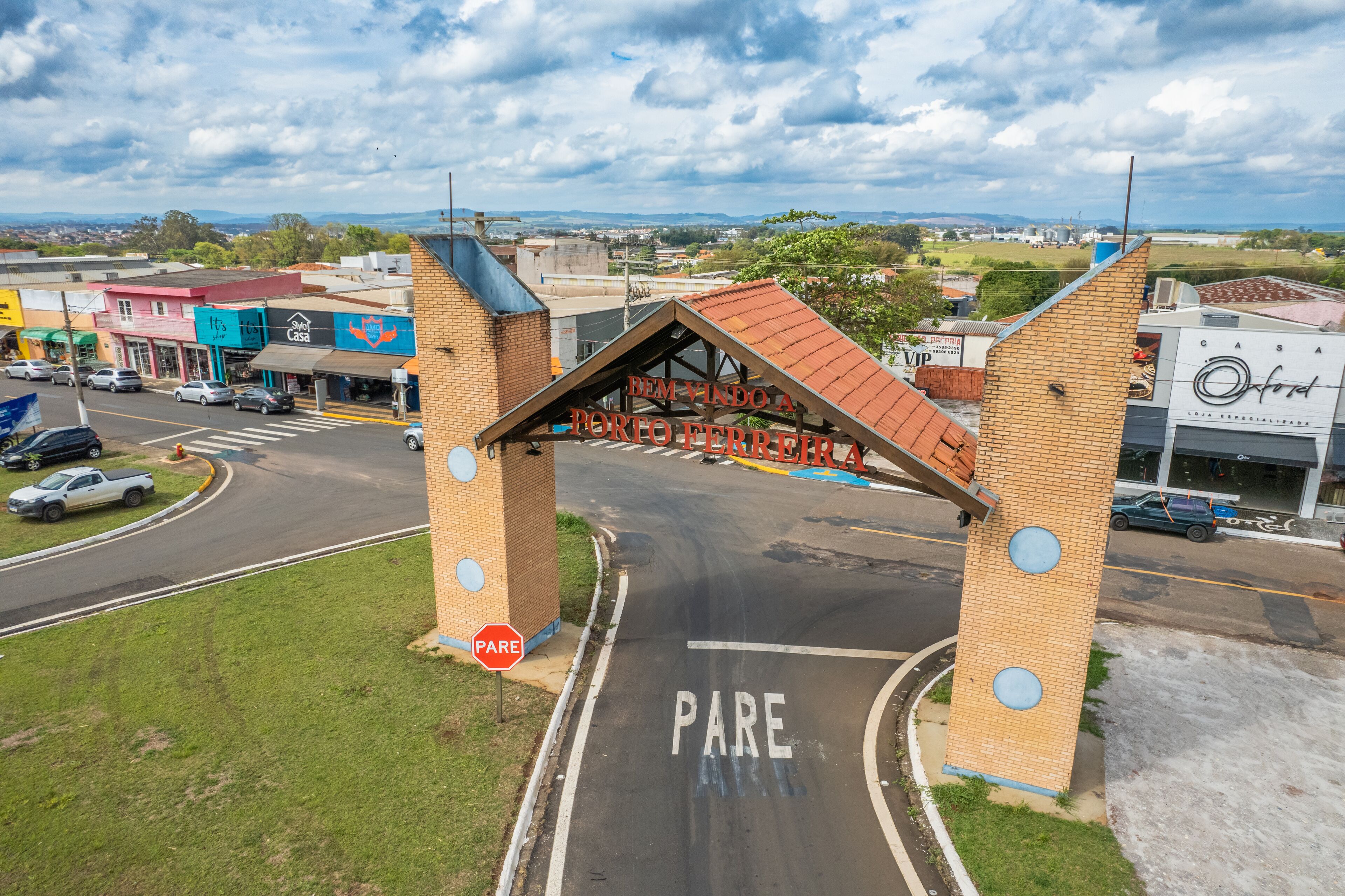 A road intersection with a 'PARE' sign and a brick structure with a red roof.