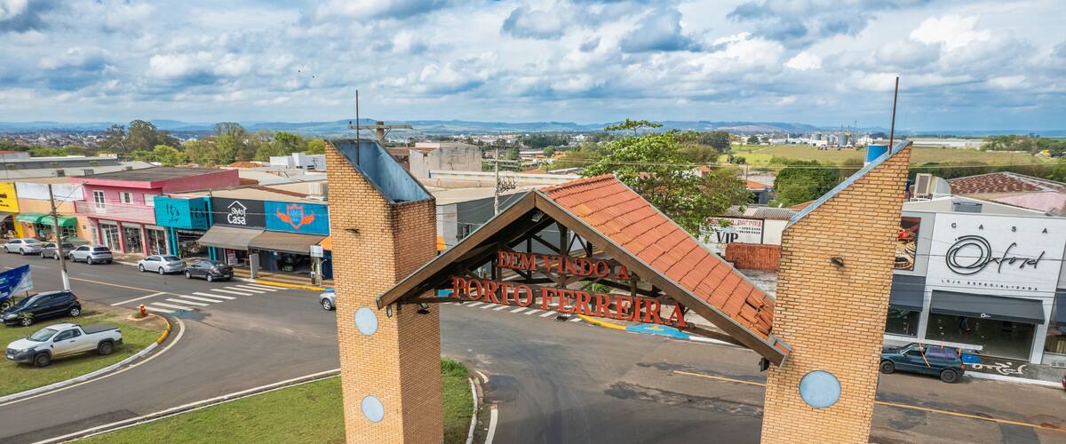 A road intersection with a 'PARE' sign and a brick structure with a red roof.