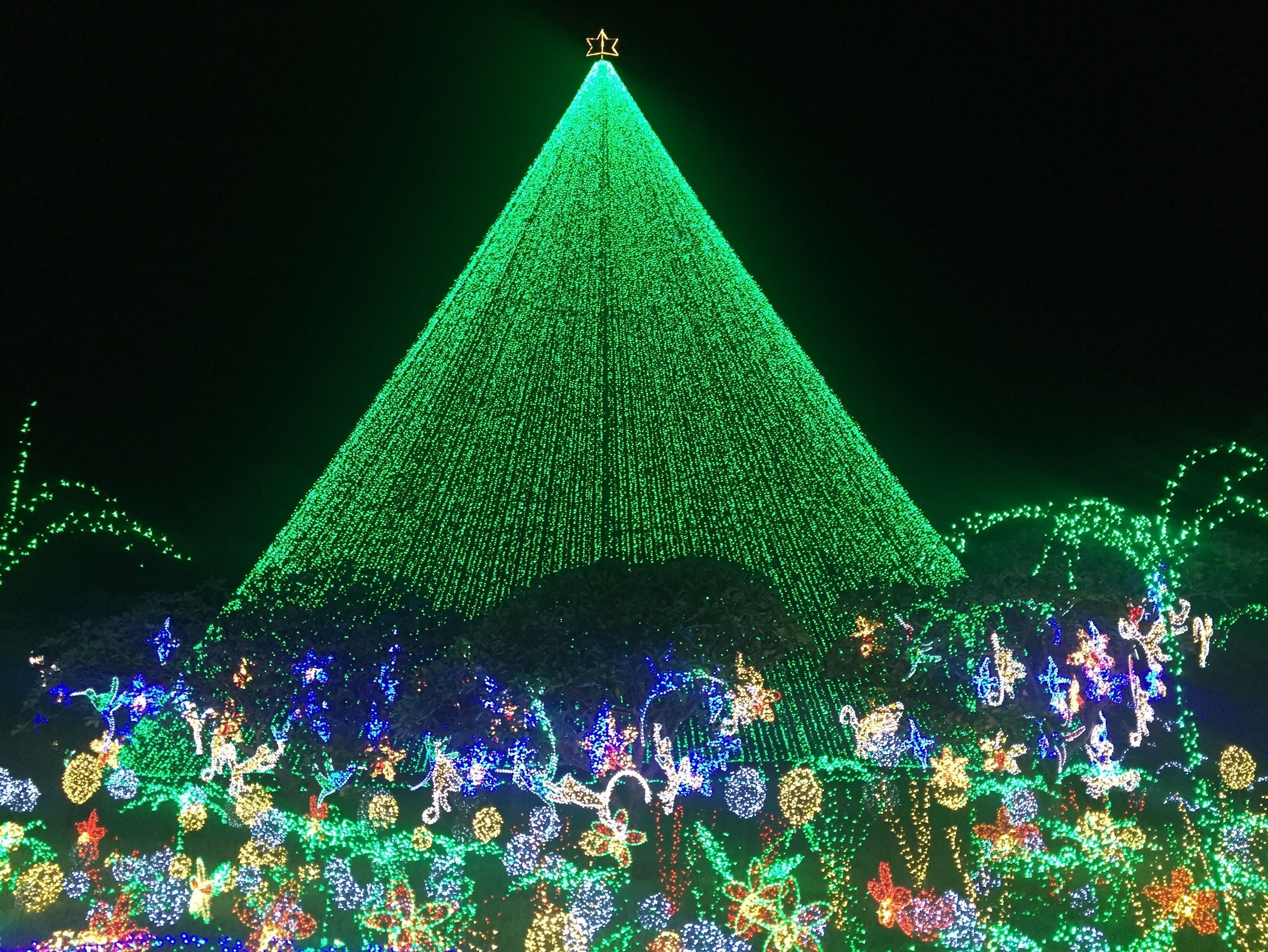 A large green pyramid structure with a star on top, surrounded by colorful lights and decorations.