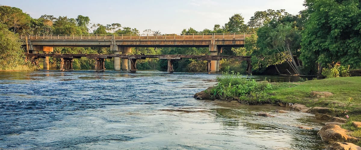A river with a bridge, rocks, and greenery.