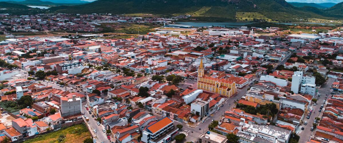 A cityscape with a prominent church, surrounded by red-roofed buildings and a mountainous backdrop.
