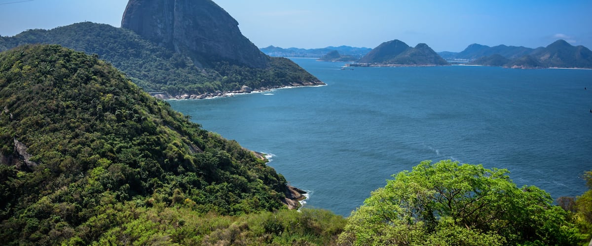 A coastal landscape with a prominent mountain and a clear view of the ocean.