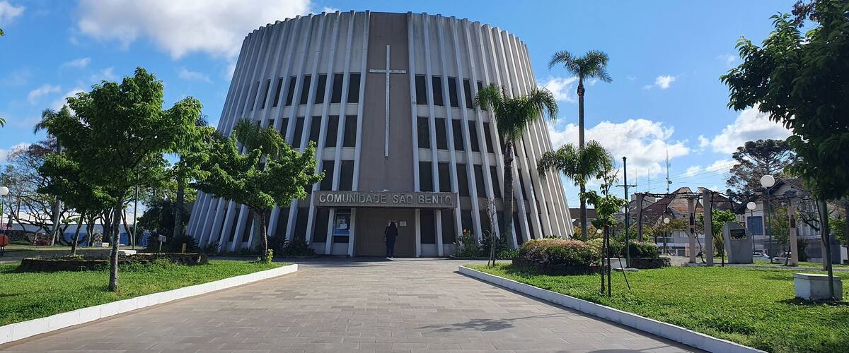 A modern building with a cross on the facade, surrounded by a well-maintained lawn and trees.