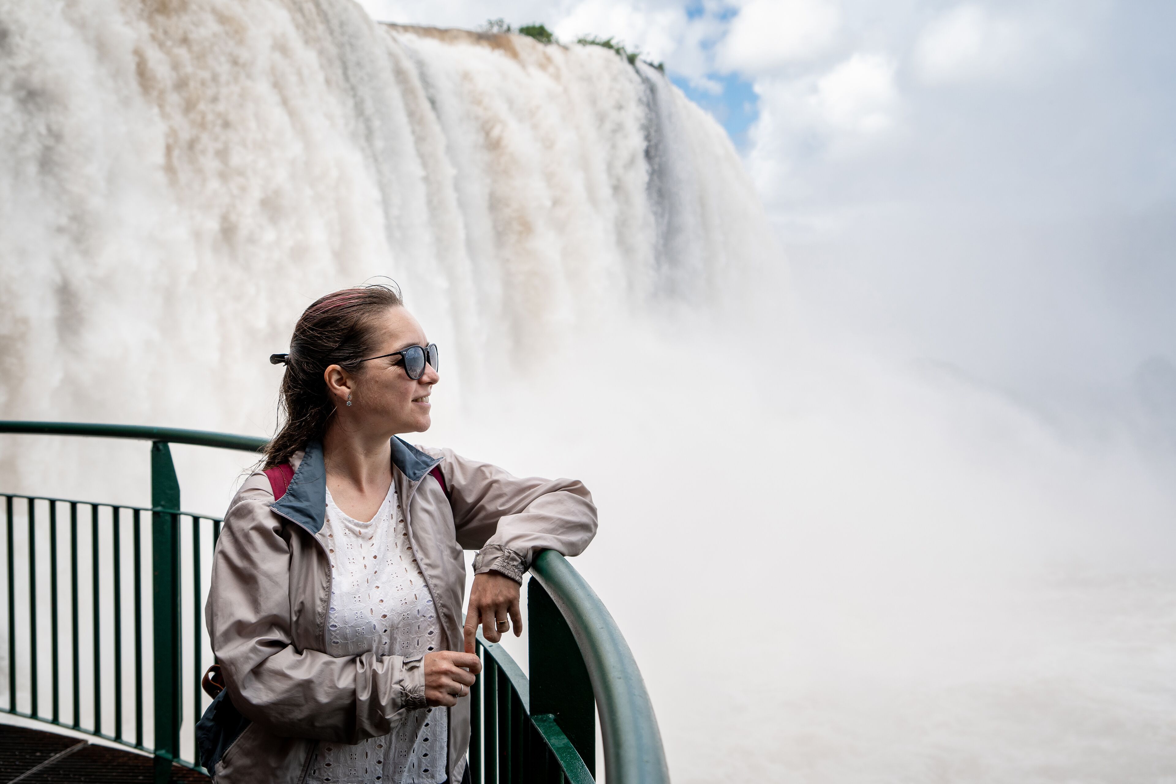 A person leaning on a railing with a waterfall in the background.