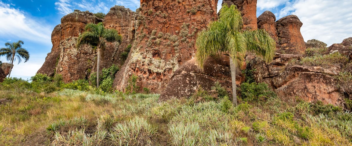 A rocky landscape with prominent red sandstone formations and sparse vegetation.