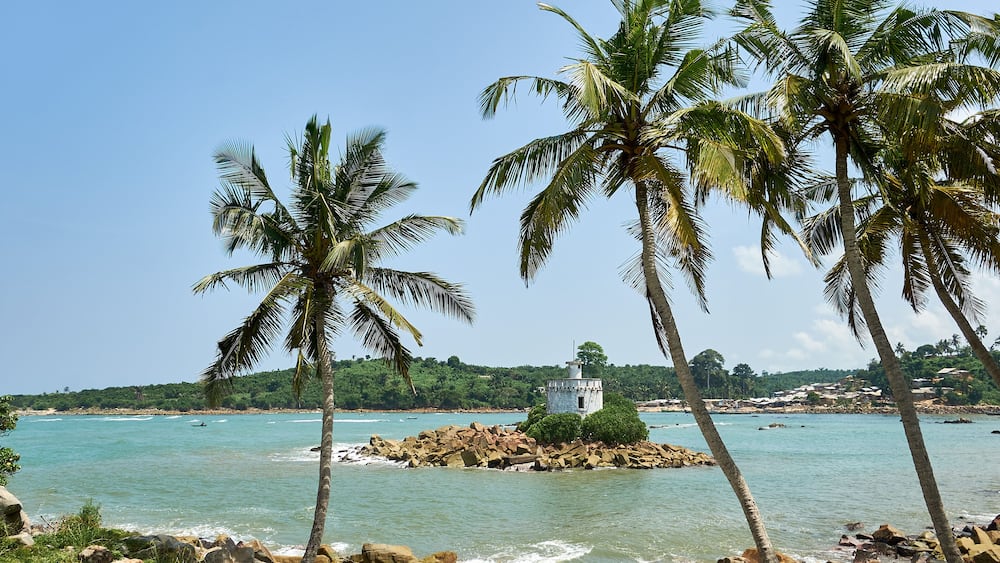 An old weathered lighthouse on a small island off the rocky shores of Dixcove, Ahanta West District, Ghana