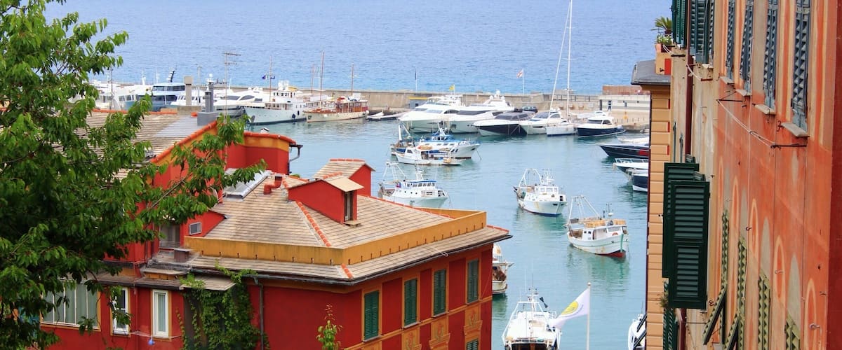 A harbor with boats, a red building, and a view of the sea.