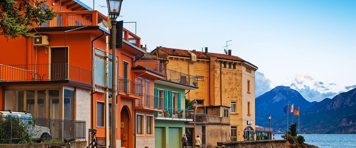 A coastal town with colorful buildings, a bicycle, and a rocky shoreline.