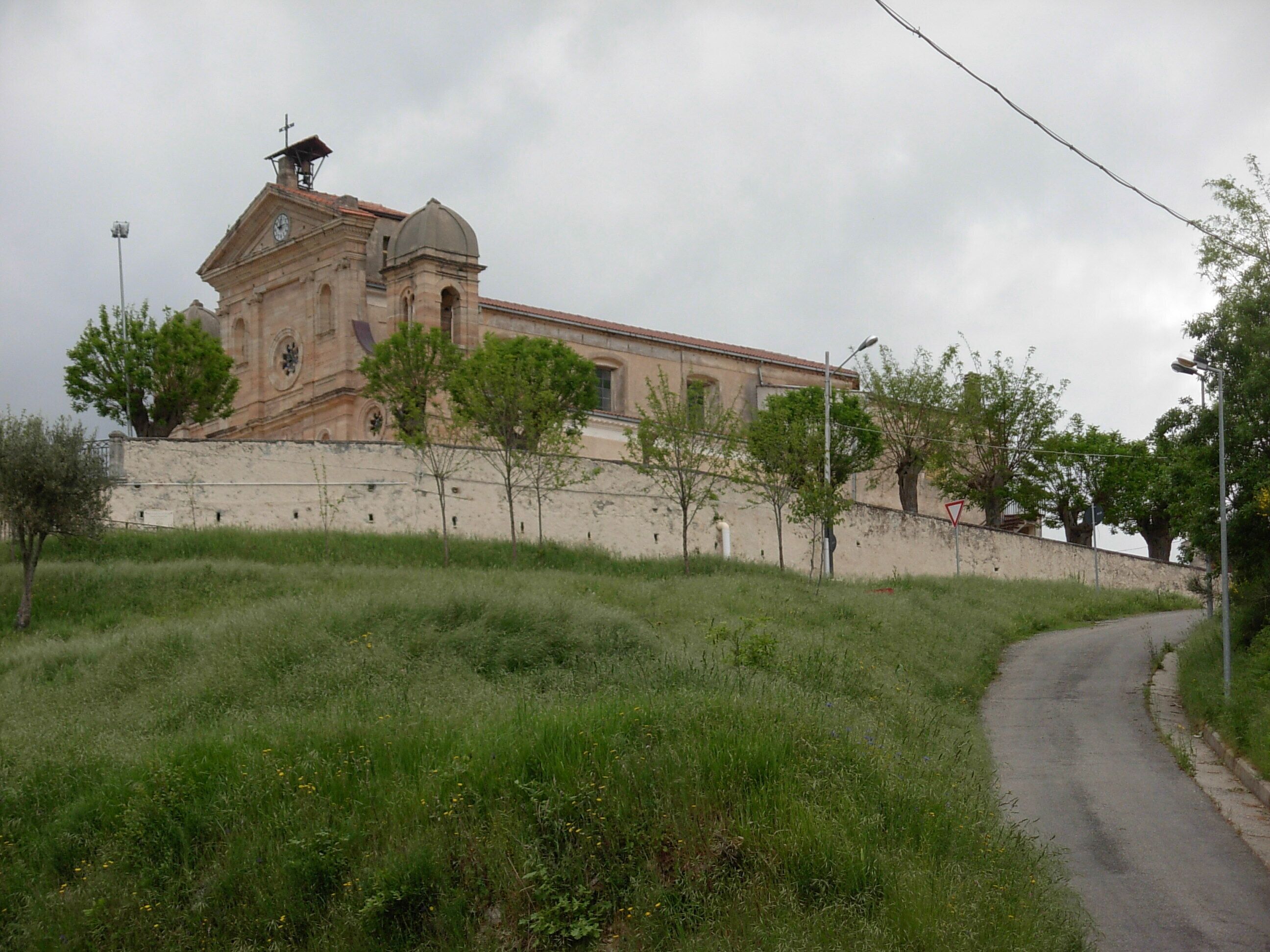 A historic building with a clock tower, surrounded by a grassy area and a paved road.