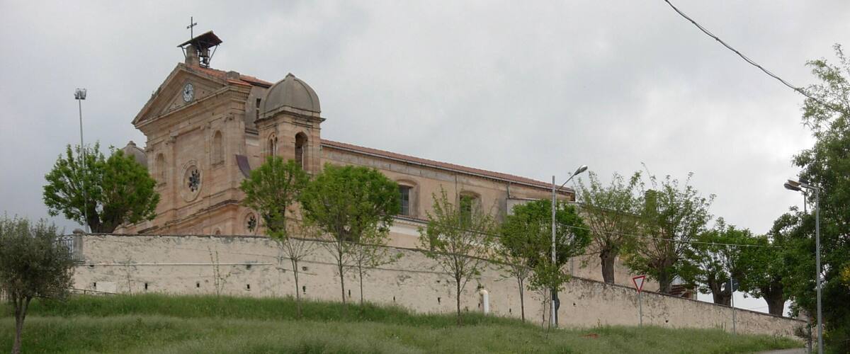 A historic building with a clock tower, surrounded by a grassy area and a paved road.