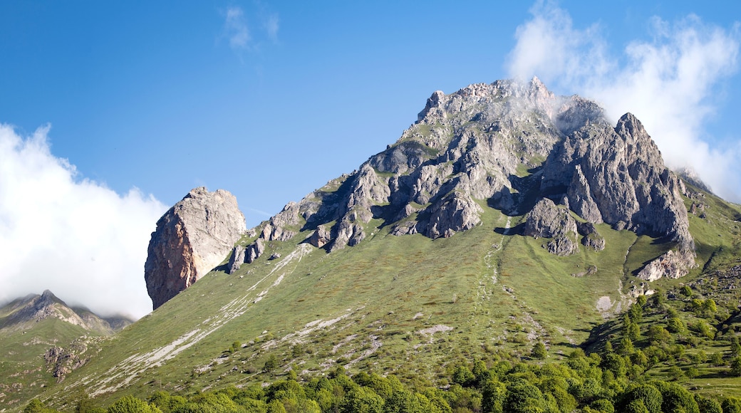 Una montaña con un pico destacado, un valle y una zona boscosa.