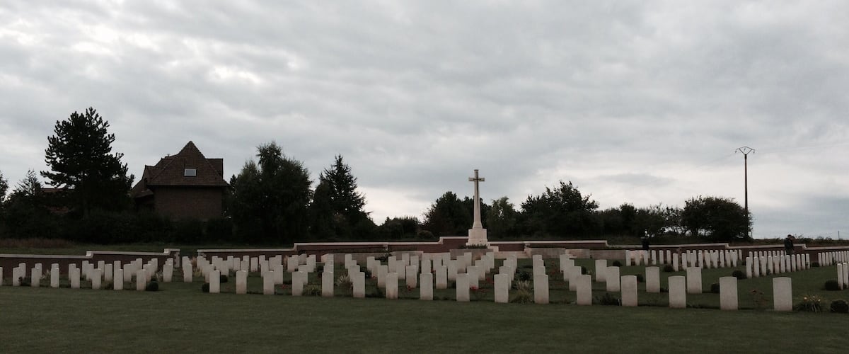 A cemetery with numerous headstones and a prominent cross monument.