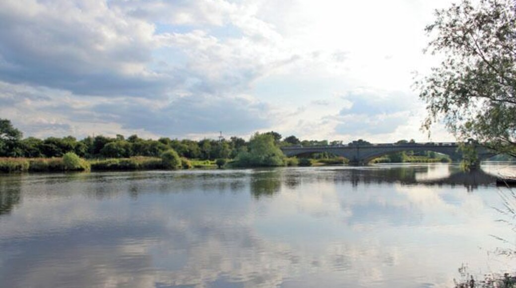 The River Trent. Looking towards Gunthorpe Bridge from the river bank by the Unicorn Hotel. Gunthorpe Bridge is the only bridge over the River Trent between Newark and Nottingham. Old Gunthorpe toll bridge, http://images.google.co.uk/imgres?imgurl=http://homepages.which.net/~shardlow.heritage/gunth.jpg&imgrefurl=http://homepages.which.net/~shardlow.heritage/shwppcards.htm&usg=__o0CWy9UhqL9o7Ju1jsVRWYTz0QM=&h=339&w=535&sz=38&hl=en&start=7&um=1&tbnid=lDpKlYKFY8o-4M:&tbnh=84&tbnw=132&prev=/images%3Fq%3Dgunthorpe%2Bbridge%26hl%3Den%26safe%3Doff%26sa%3DN%26um%3D1 , was built on the site of a ford and ferry that had existed since Roman times. Built in 1875 by the Gunthorpe Bridge Company who raised £7,500 through a share issue, it was a largely iron structure crossing the Trent: see 956029 and 955984. The tolls were horse and carriage 1/-, horse and wagon 6d, horse alone 3d, people and passengers 1d, motorcycles 3d, cars 1/- and lorries 2/6. In 1925 the Gunthorpe Bridge Act empowered the council to buy the owners out, demolish the bridge and replace it with the present one, seen here, a couple of hundred yards up stream. This believed to be the first toll bridge in the country to be replaced by a free one.