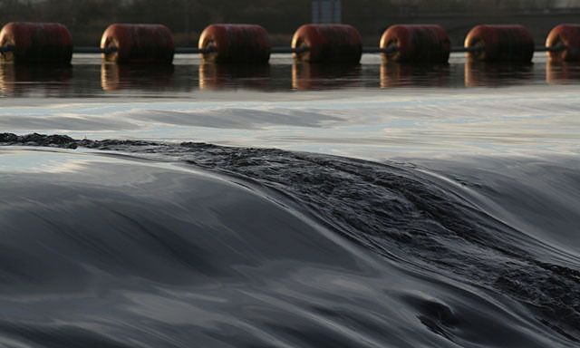 A waterfall with a smooth flow and several orange buoys in the background.