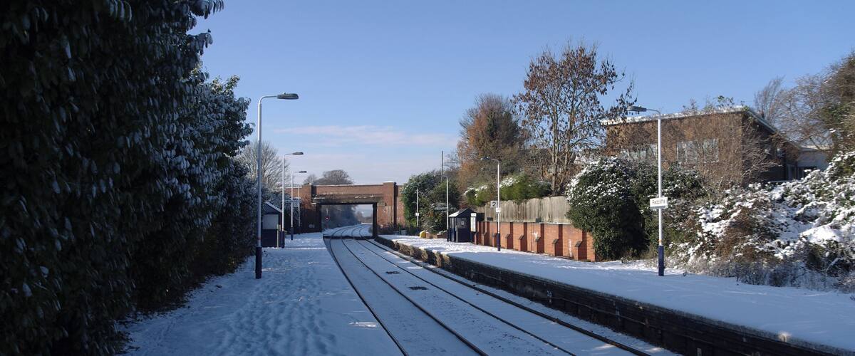 A snow-covered railway track with a bridge in the background.