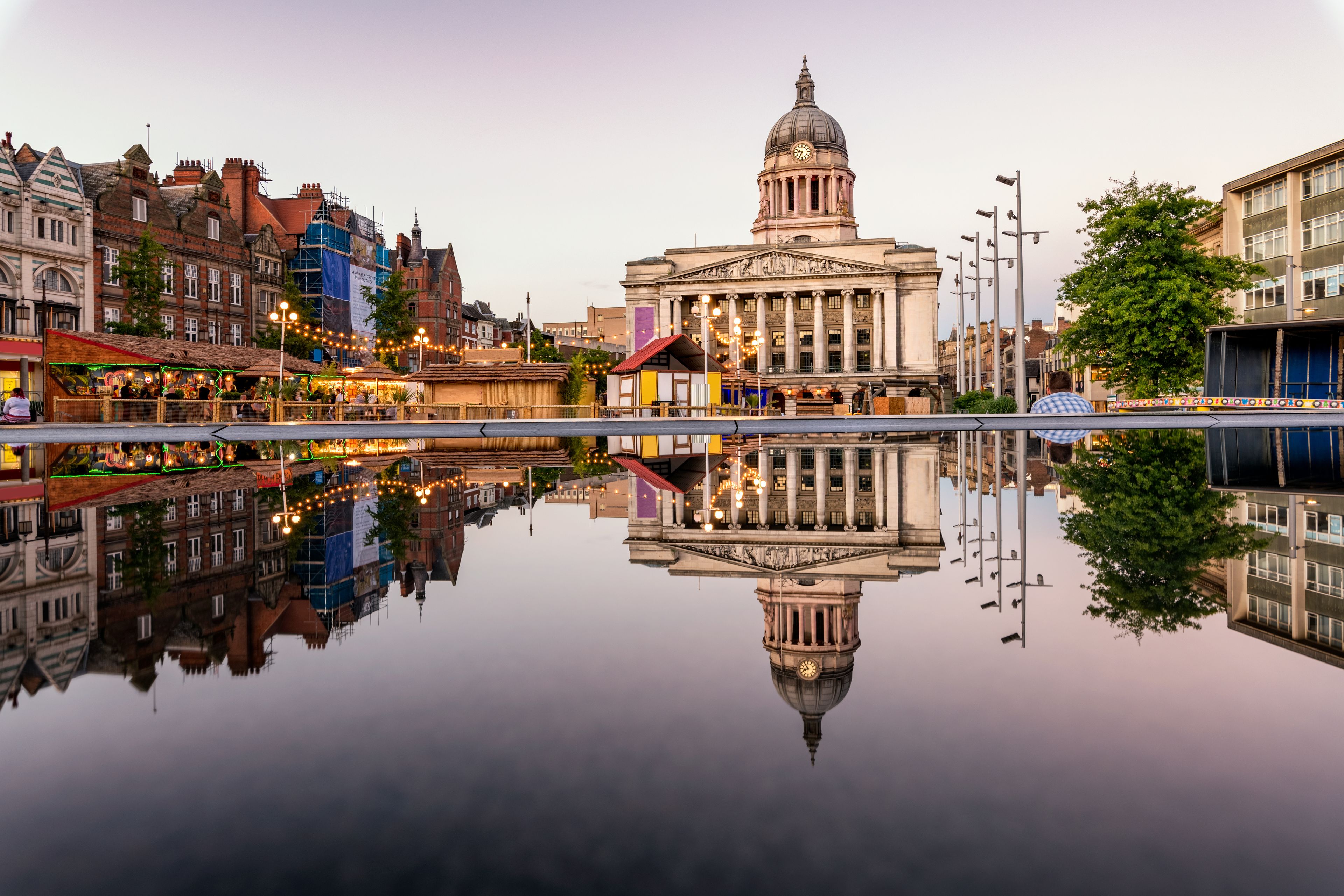 A historic building with a dome and columns, reflecting in a calm body of water.
