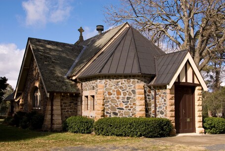 A stone church with a pointed roof and a cross on the front.
