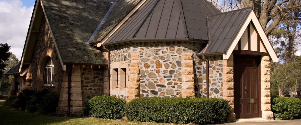 A stone church with a pointed roof and a cross on the front.