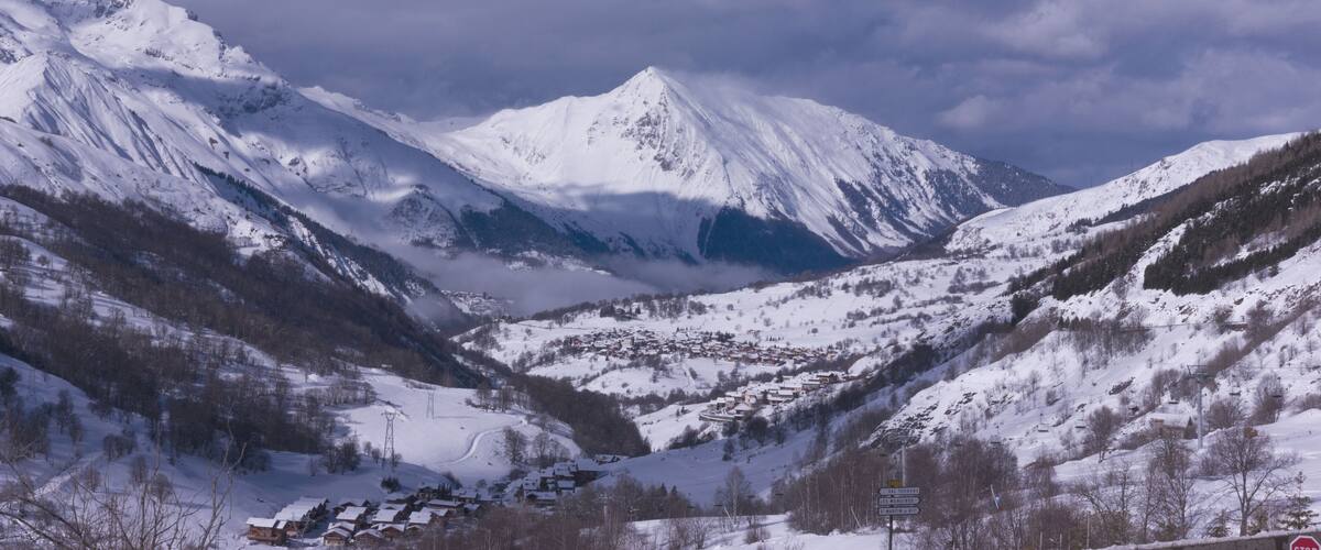 A snow-covered mountain range with a village nestled in a valley.