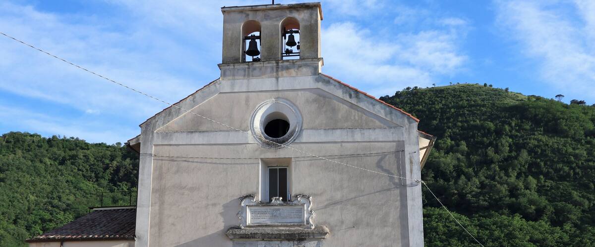 A small church with a bell tower, a wooden door, and a bell.