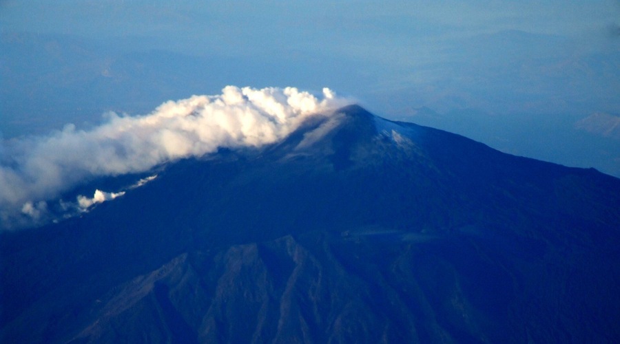 Une montagne dont le sommet est enveloppé de nuages, avec un ciel dégagé.
