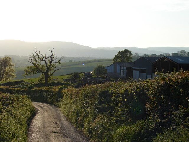 Un camino rural con una casa y un granero al fondo.