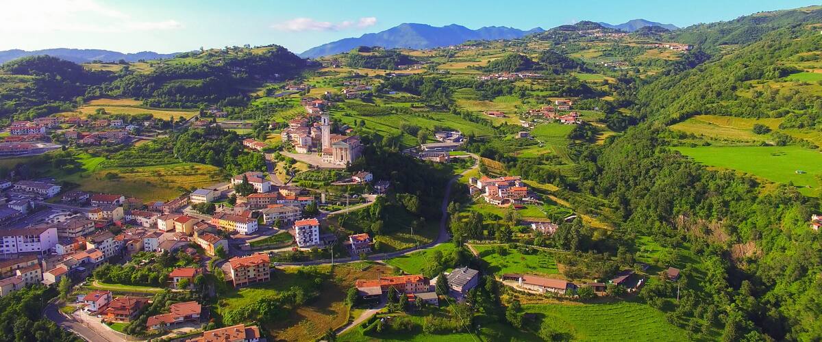 A mountainous landscape with a town nestled in the valley, surrounded by lush greenery and distant mountains.