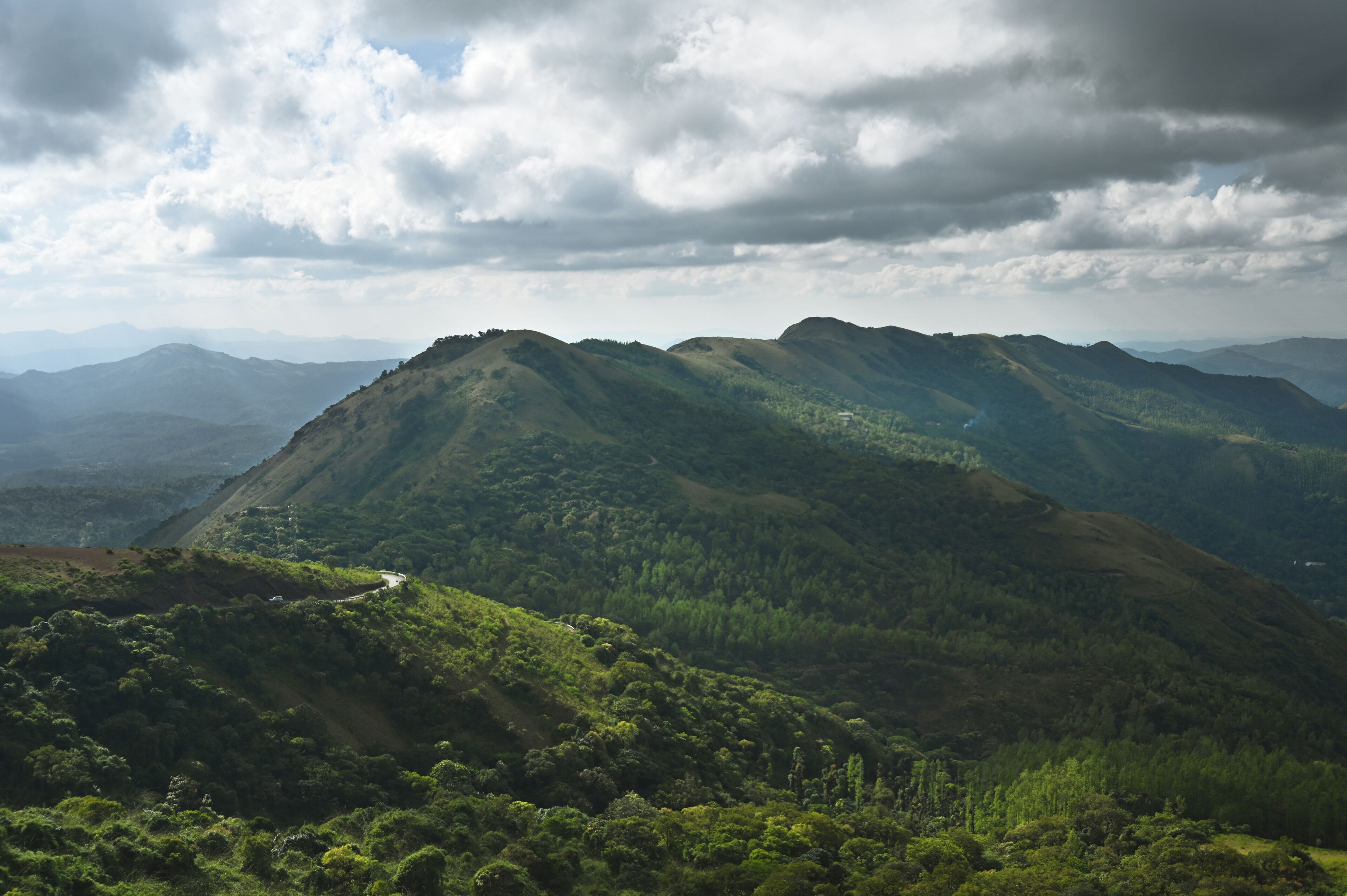 A mountainous landscape with a winding road and dense forest.