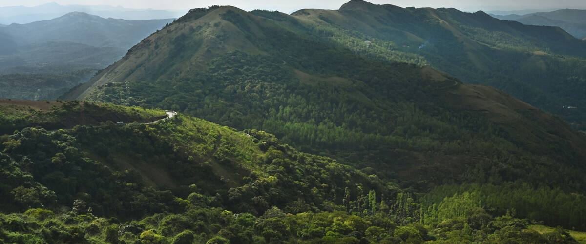 A mountainous landscape with a winding road and dense forest.