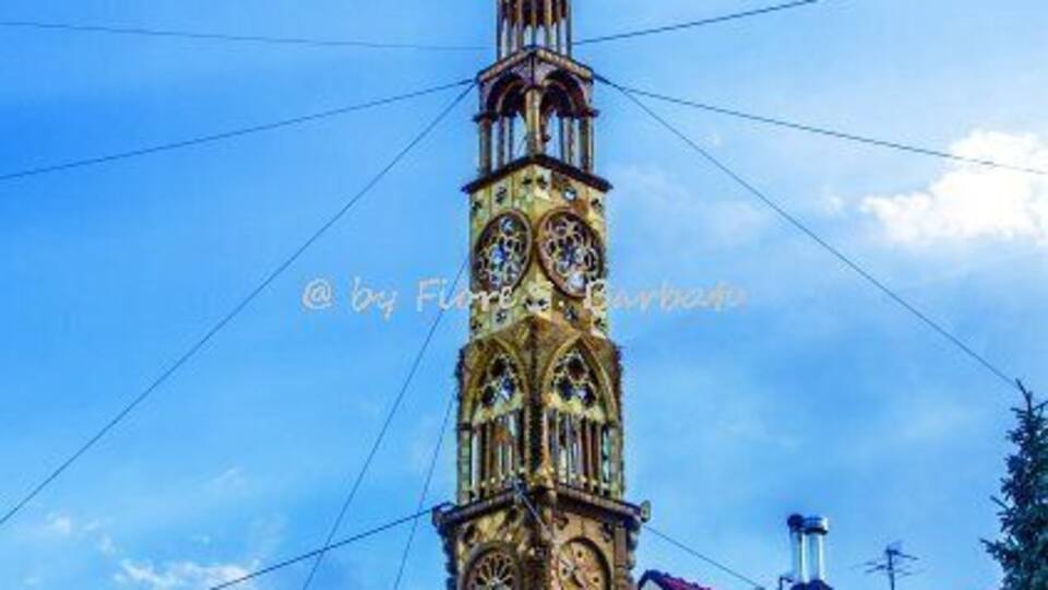 A tall, ornate clock tower with intricate designs and a pointed spire.