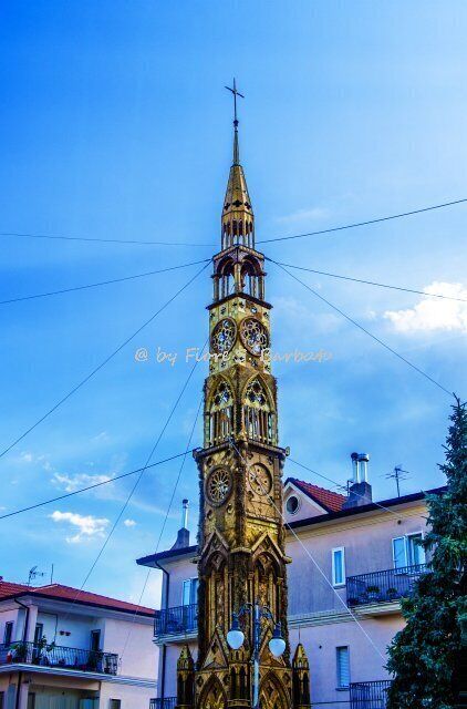 A tall, ornate clock tower with intricate designs and a pointed spire.