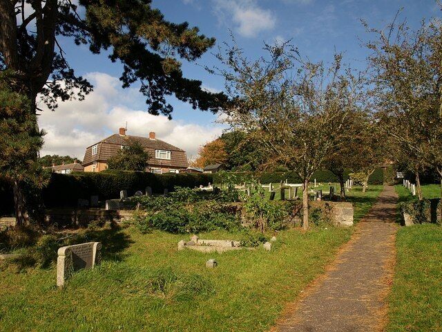 Churchyard, Church of All Saints, Norton Fitzwarren. The northern part of the churchyard of 1002129 crosses a gridline. The house on the left is on the northern arm of Hilly Park, which is where this path is destined to lead.