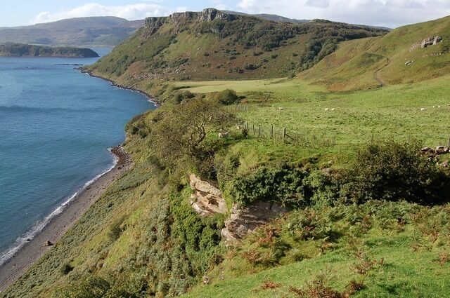 Am Bile Looking along the Bile, where there is an area of grazing land below the township of Torvaig. It can be accessed from above by an ancient cart track. The shoreline below is Port a'Bhata (port of the boats) on the Sound of Raasay. Beyond the Bile is Ben Chracaig, guarding the entrance to Portree Bay. In the centre foreground is an exposure of Mesozoic rock, part of the layer that supports the more recent basaltic plateau lavas that make up most of north Skye.