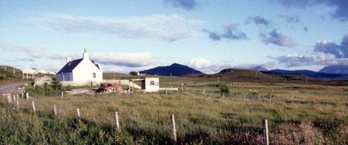 A white church in a grassy field with mountains in the background.