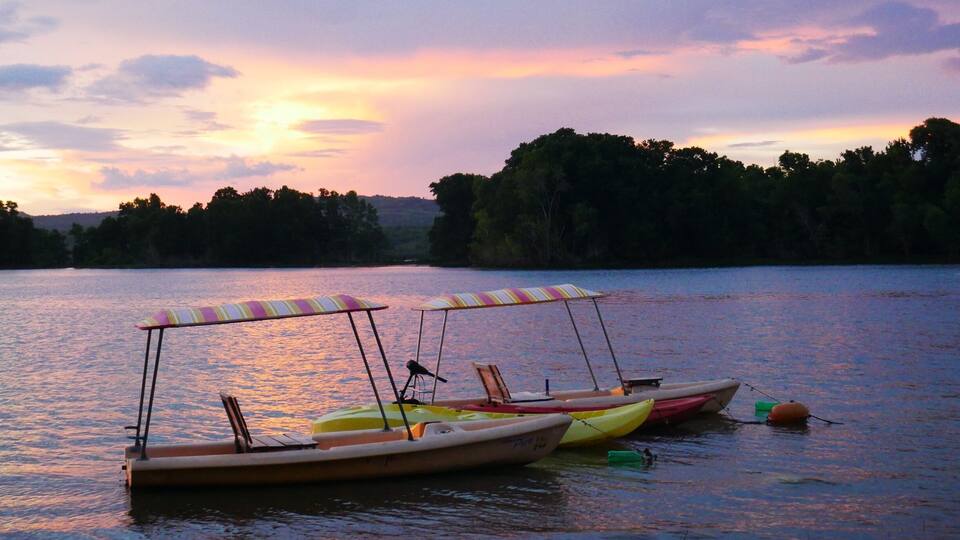 A calm lake at sunset with two canoes and a kayak docked.