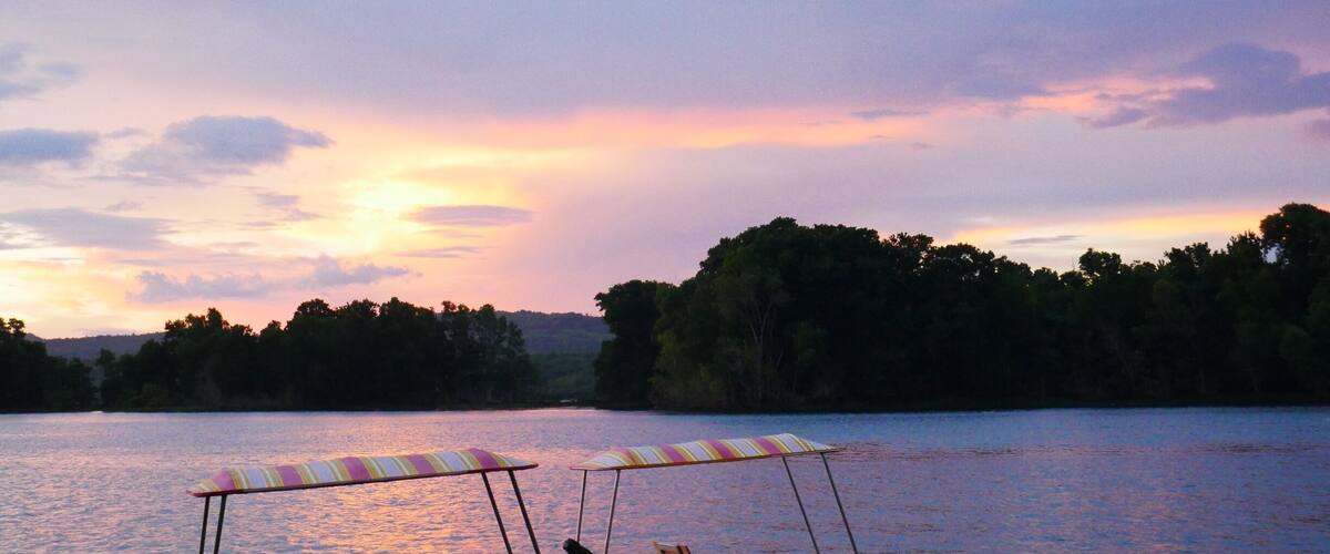 A calm lake at sunset with two canoes and a kayak docked.