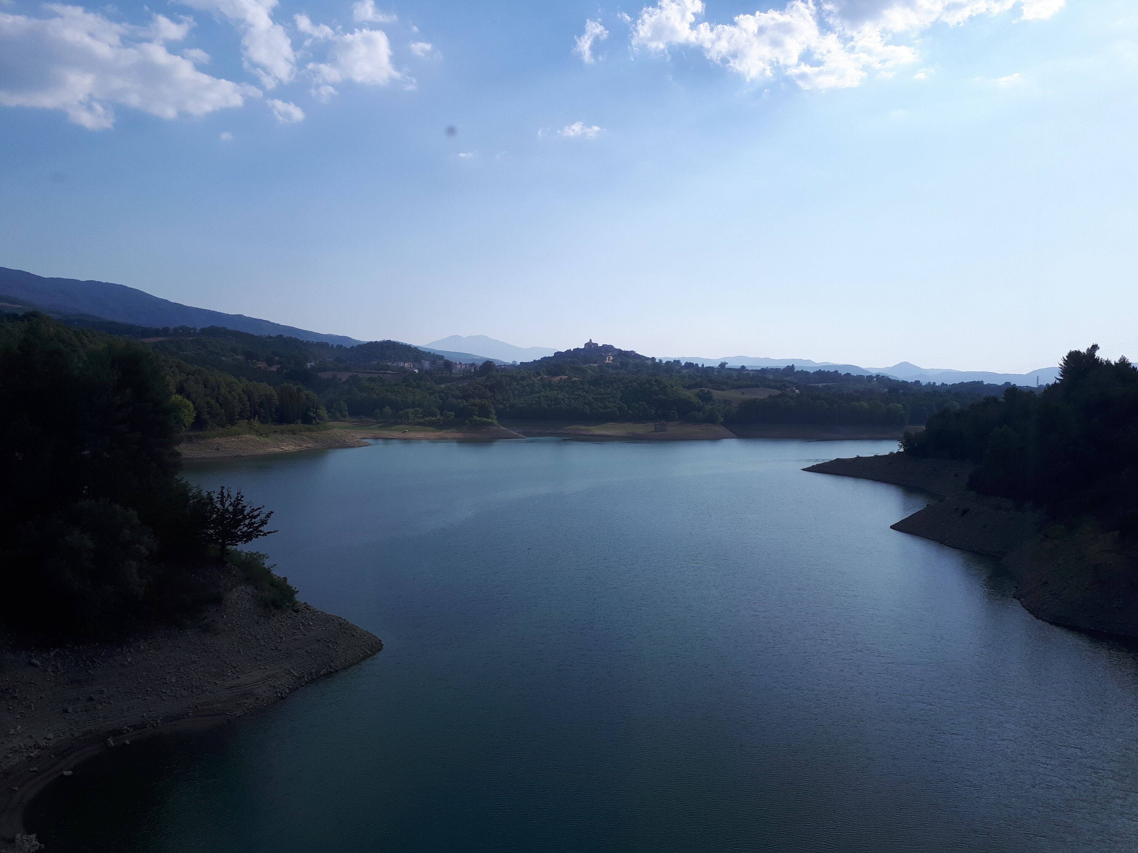 A calm lake surrounded by hills and trees.