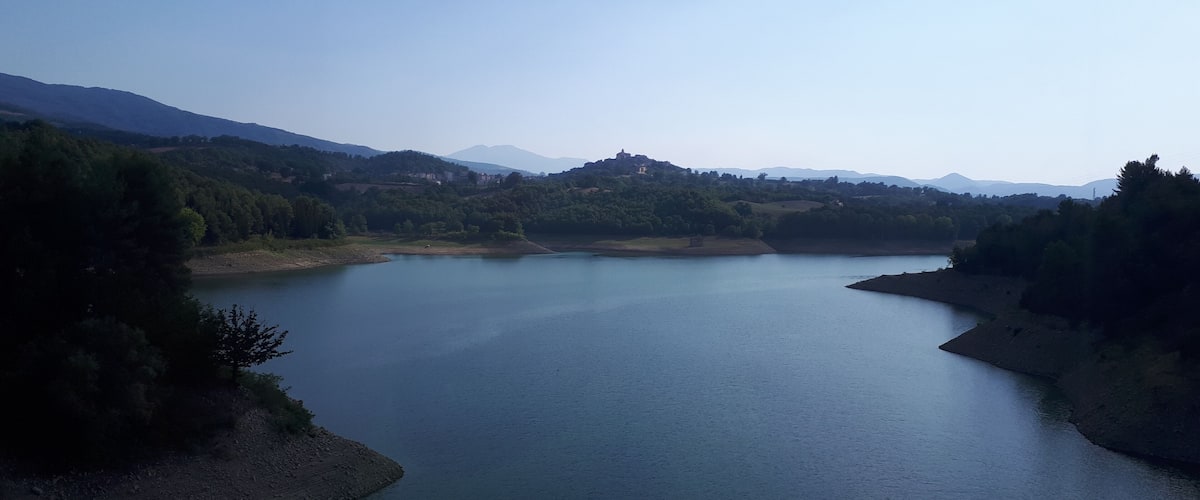 A calm lake surrounded by hills and trees.