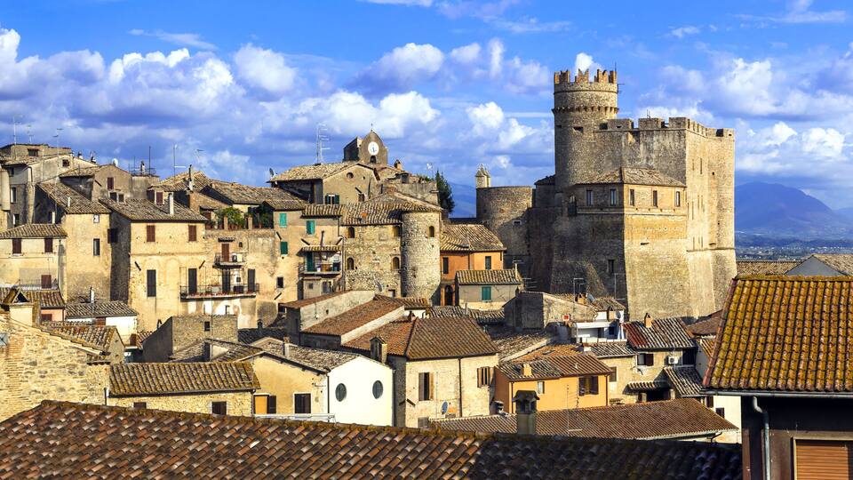 A historic town with medieval architecture, including a prominent castle and stone buildings with tiled roofs.