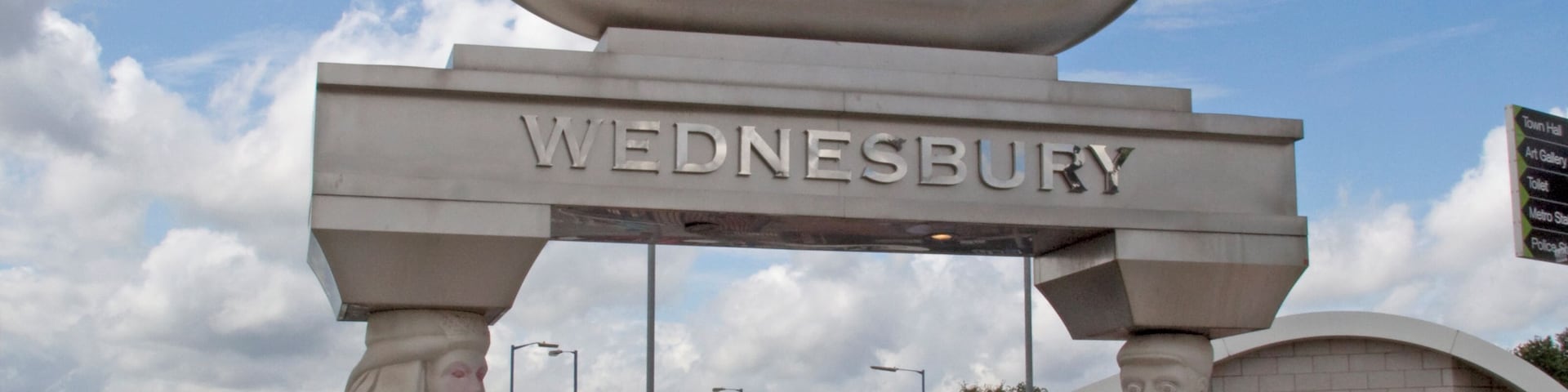 The Caryatid Gateway features two carved stone caryatids, one male and one female, each representing different aspects of Wednesbury history. The female figure represents Ethelfleda, daughter of King Alfred, who fortified Wednesbury against the Danes. The male figure represents a tube maker, Wednesbury being famous for the manufacture of tubes, the process having been patented in the nineteenth century by Cornelius Whitehouse. The tube reference is continued in the polished stainless steel inverted tubular arch 'carried' by the caryatids.