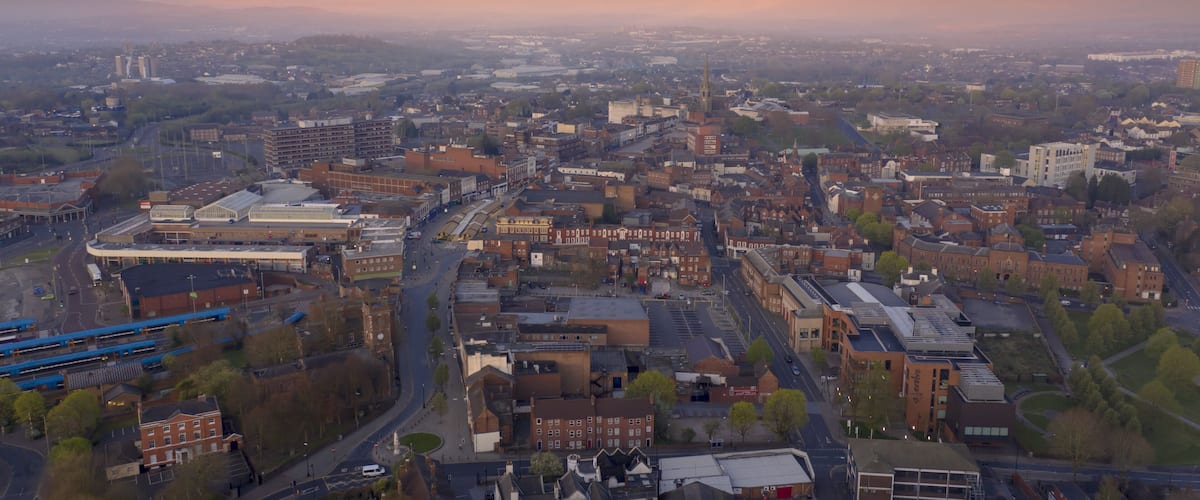 An aerial view of a city with a prominent church spire, a large industrial area, and a mix of residential and commercial buildings.