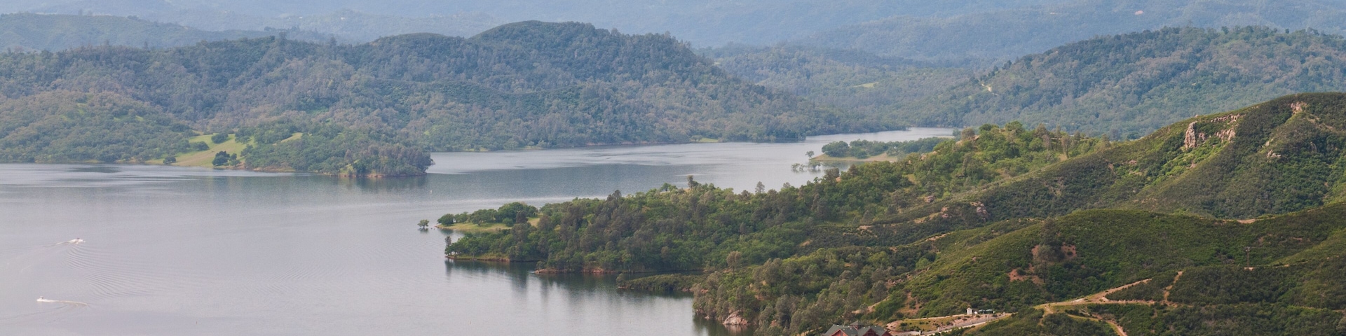 A lake surrounded by forested hills and a distant mountain range.