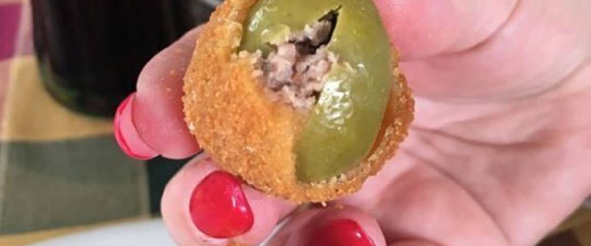 A hand holding a fried green chili pepper.