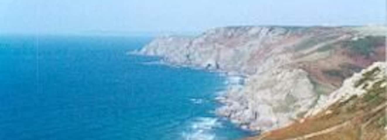 Paisagem costeira com falésias e mar azul cristalino.