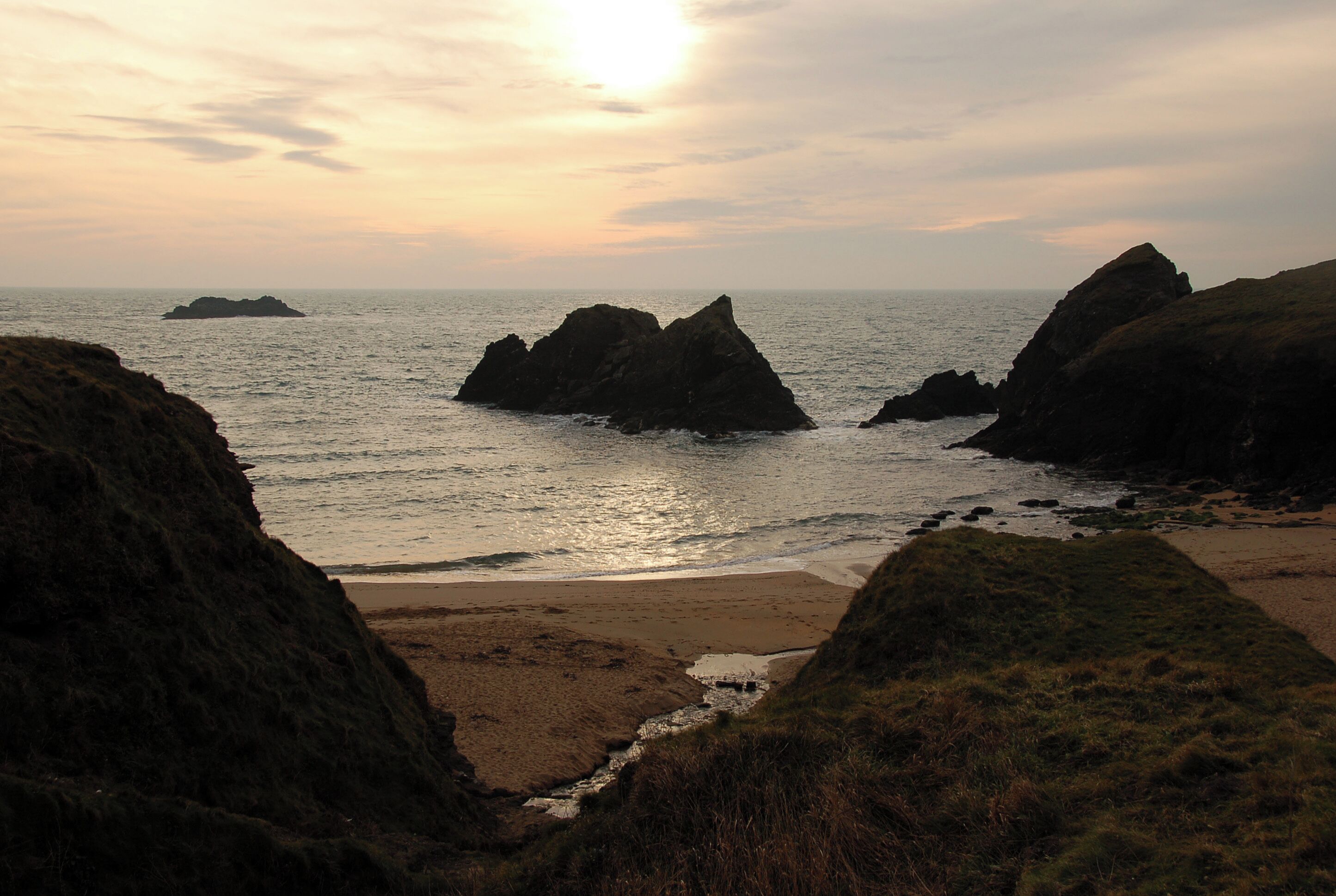 A coastal landscape with rocky outcrops and a beach.