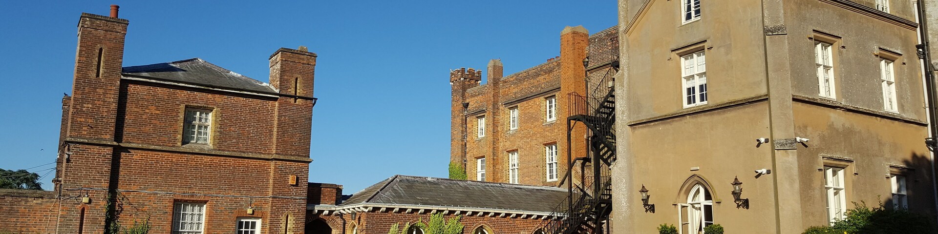 A historic building with a brick tower and a large, beige facade.