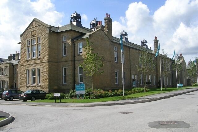 A historic building with a clock tower, a street sign, and parked cars.