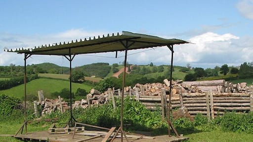 Felled trees and rickety shelter off the B4221 The red stripe down the centre of the field in the distance is part of the construction of the Felindre to Tirley pipeline.