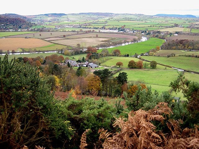 A rural landscape with fields, a river, and a small village.