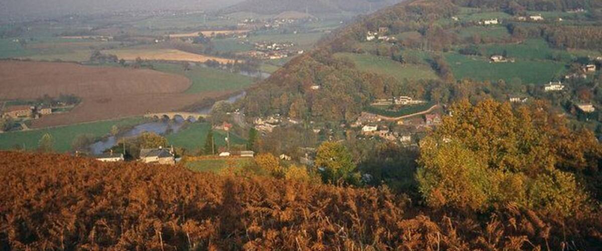 A valley with a river, fields, and scattered houses.